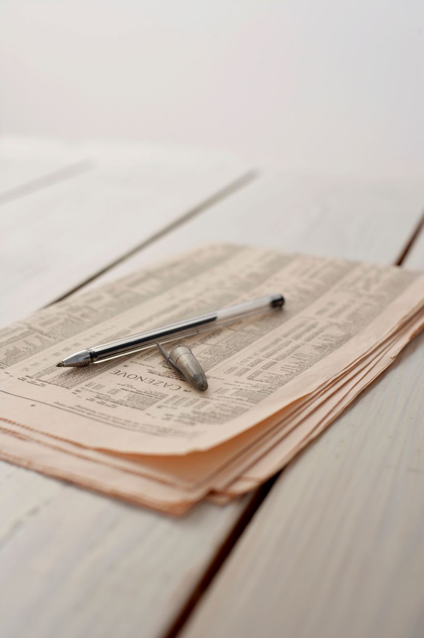 A pen resting on an open notebook of newsprint, representing editorial craft and careful judgment.